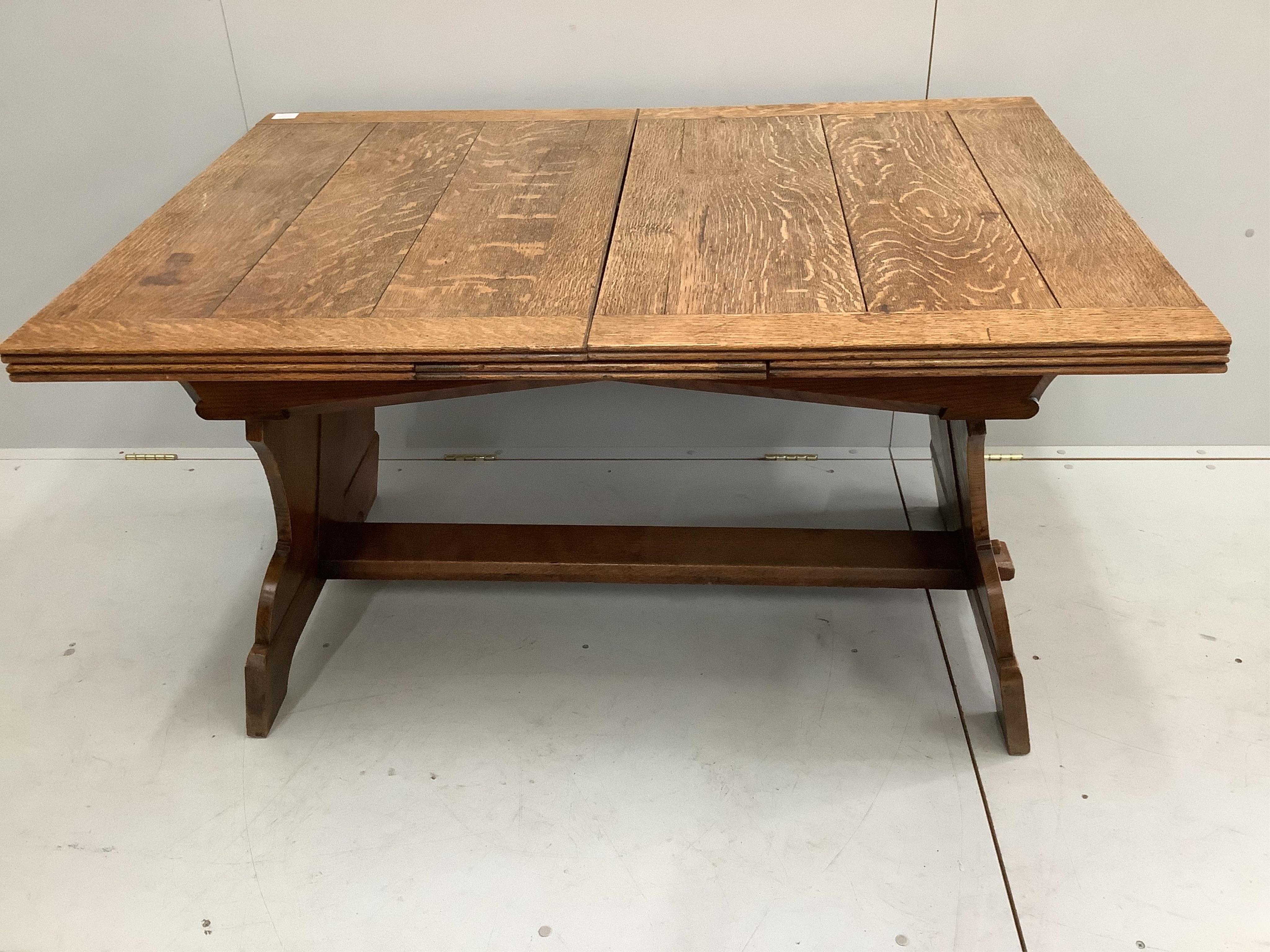 An oak draw leaf dining table, the shaped end standards united by flat stretcher, width 130cm, depth 91cm, height 72cm. Condition - fair